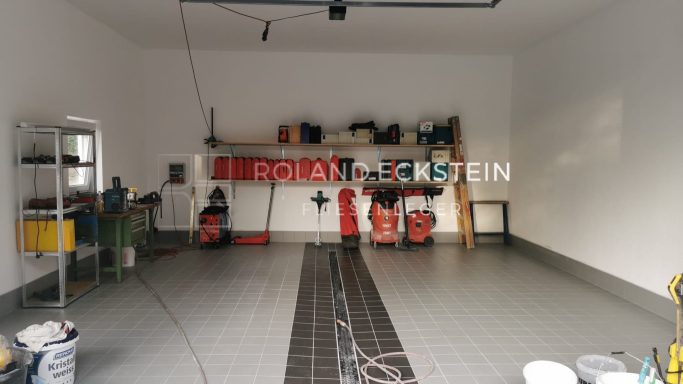 Gepflegter Garagenraum mit Regalen, Werkzeugen und Staubsauger.