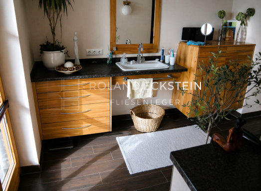 Modernes Badezimmer mit Holzschränken, Waschbecken und Pflanzenarrangement.