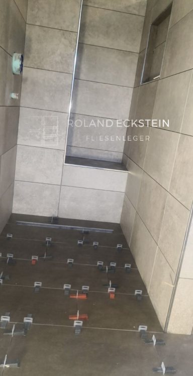 Fliesenlegerarbeiten in einem Badezimmer mit verlegten Fliesen und Baustellenumgebung.
