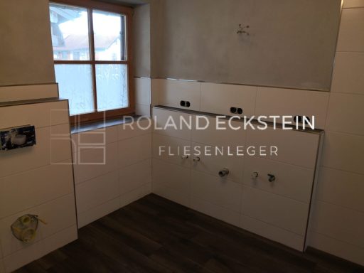 Unvollendeter Raum mit gefliesten Wänden und Fenstern, bereit für die Installation.