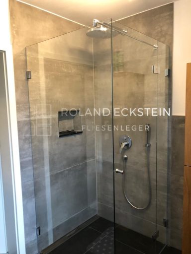 Moderne Dusche mit Glaswänden und grauen Fliesen.