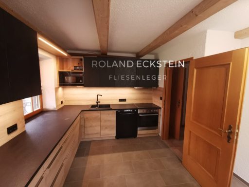 Moderne Küche mit Holzregalen, schwarzen Geräten und Holzverkleidung.
