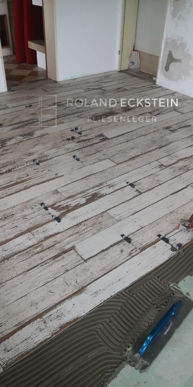 Holzboden mit verlegten Platten, einige Platten mit Abstandhaltern fixiert.