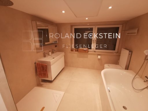 Helles Badezimmer mit Badewanne, Waschbecken und zwei Fenstern.