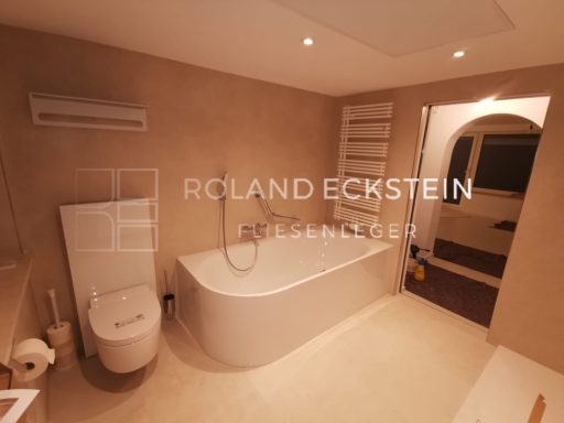 Ein modernes Badezimmer mit Badewanne, WC und Waschbecken in neutralen Farben.