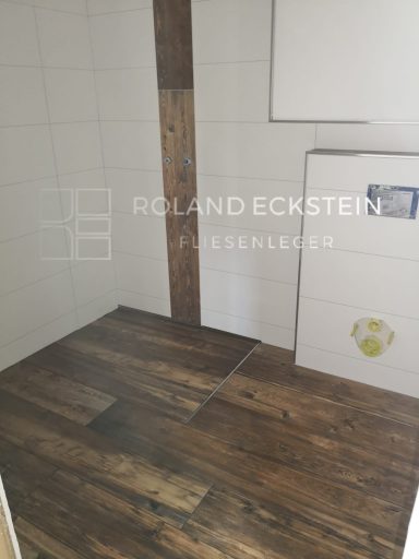 Heller Raum mit Holzfußboden und weißen Fliesen an der Wand.