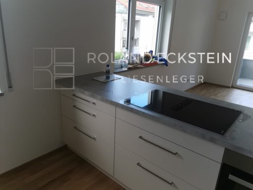 Moderne Küchenzeile mit Kochfeld und Spüle, helle Wände und Holzfußboden.