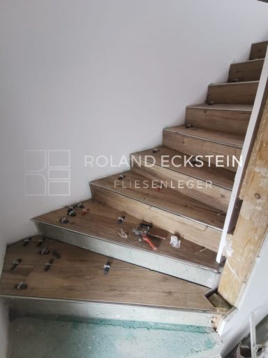 Holztreppe mit unvollständigem Geländer und Werkzeug auf den Stufen.