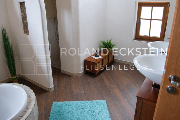Helles Badezimmer mit zwei Waschbecken, einer Badewanne und Pflanzen.