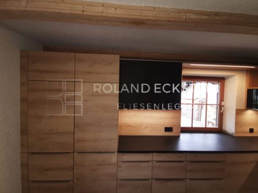 Moderne Küche mit Holzschränken und einem Fenster, das natürliches Licht hereinlässt.