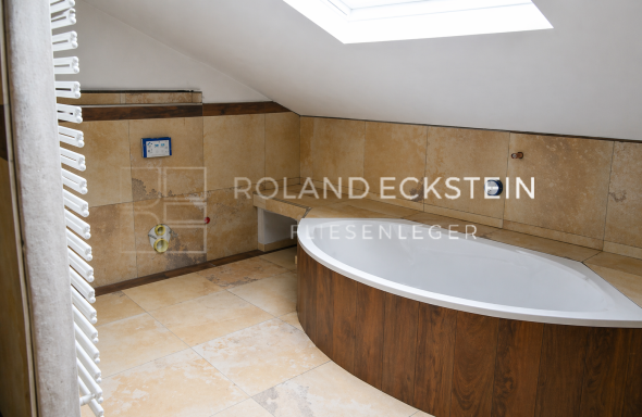 Badezimmer mit freistehender Badewanne und Holzverkleidung, helle Wände und Dachfenster.