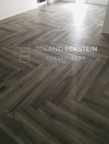 Holzboden in Fischgrätmuster, grau und beige mit mattem Finish.