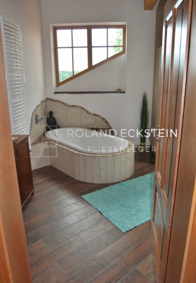 Heller Badezimmer mit moderner Badewanne, Holzdetails und grünem Teppich.